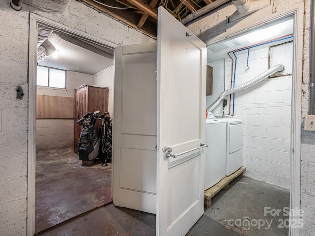 basement featuring concrete block wall and washing machine and clothes dryer