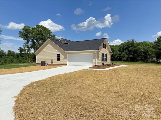 view of side of home featuring a lawn, driveway, cooling unit, and a garage