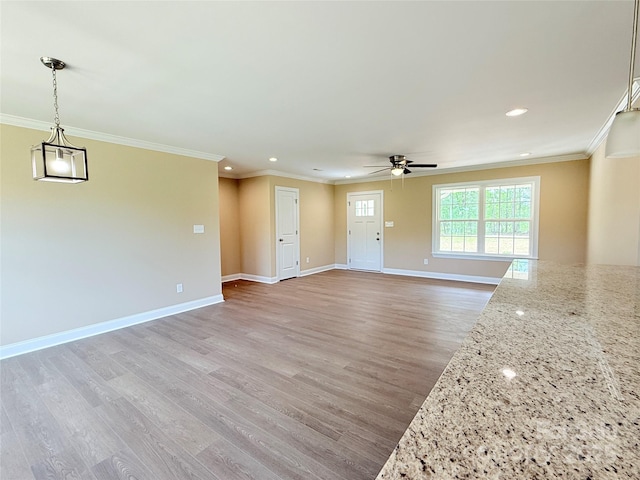 unfurnished living room featuring light wood-type flooring, crown molding, baseboards, and ceiling fan