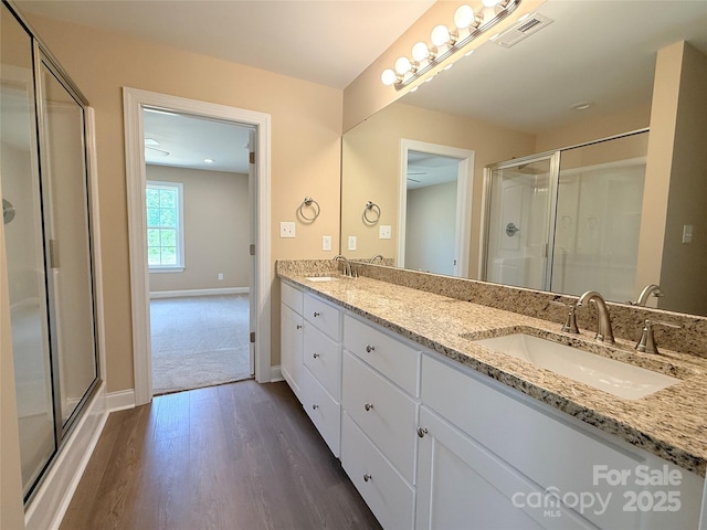 full bath featuring baseboards, a sink, wood finished floors, and a shower stall