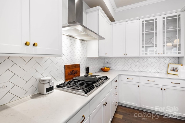 kitchen with wall chimney exhaust hood, stainless steel gas cooktop, ornamental molding, white cabinets, and light countertops
