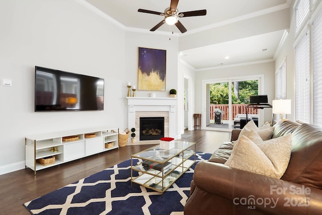 living area with ceiling fan, wood finished floors, crown molding, a fireplace with flush hearth, and baseboards