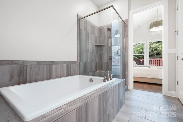 full bath featuring a stall shower, a relaxing tiled tub, and ensuite bathroom
