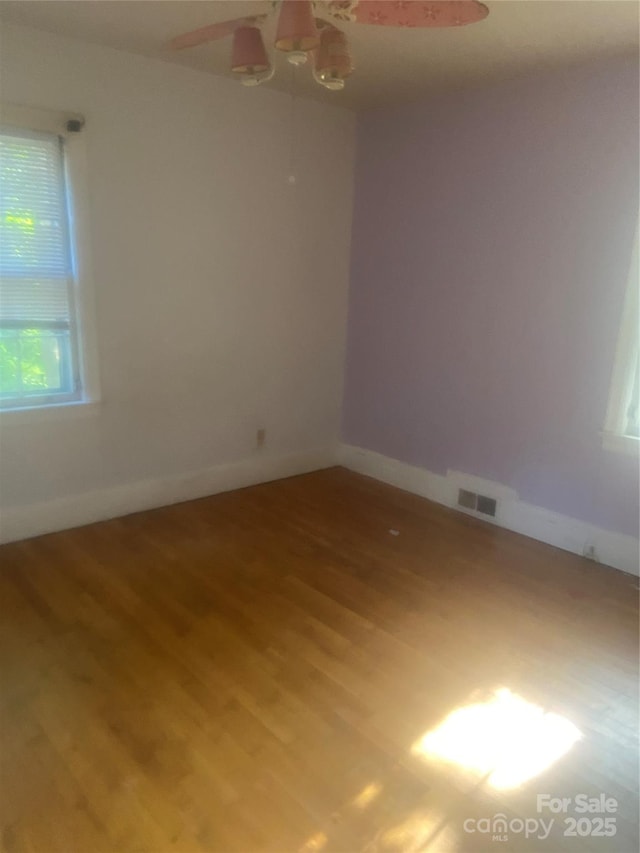 unfurnished room featuring baseboards, a ceiling fan, wood finished floors, and visible vents