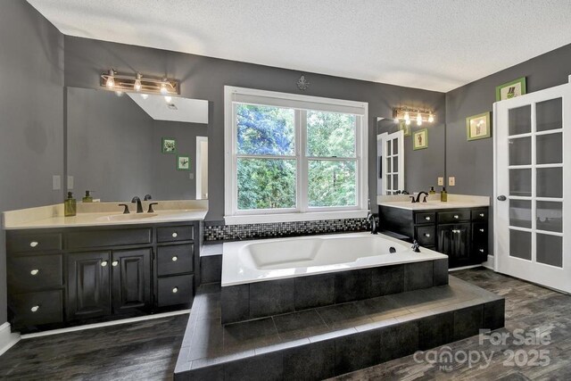 8524 Quarters Ln, Mint Hill, NC 28227 - full bathroom with a textured ceiling, a bath, two vanities, and wood finished floors