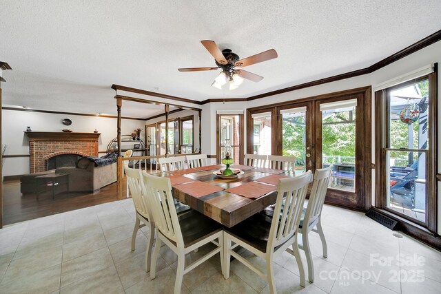 8524 Quarters Ln, Mint Hill, NC 28227 - dining area featuring crown molding, a textured ceiling, light tile patterned floors, a brick fireplace, and ceiling fan