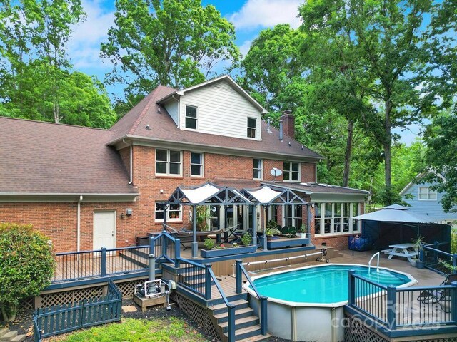 8524 Quarters Ln, Mint Hill, NC 28227 - back of house featuring a wooden deck, brick siding, an outdoor pool, and a gazebo
