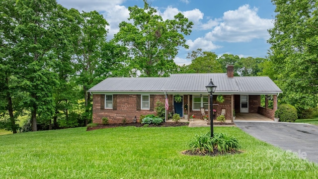 single story home featuring aphalt driveway, metal roof, brick siding, a front lawn, and an attached carport