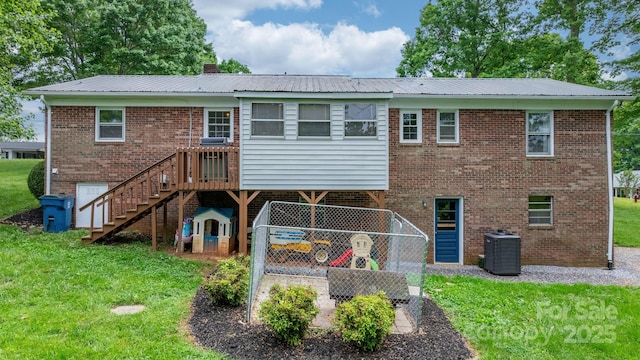 back of house with brick siding, a lawn, and central AC