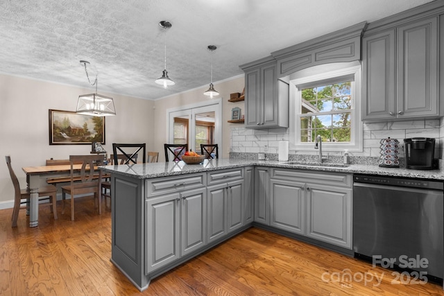 kitchen with dishwasher, light wood-style floors, gray cabinets, a sink, and backsplash