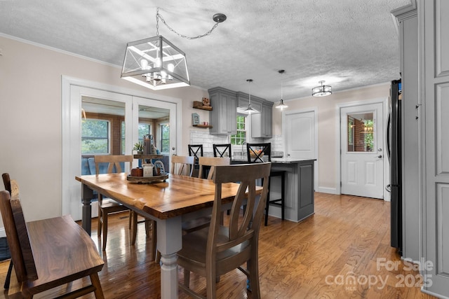 dining room featuring crown molding, a textured ceiling, and light wood-style floors