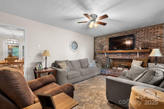 living room featuring a textured ceiling, ceiling fan with notable chandelier, and a fireplace