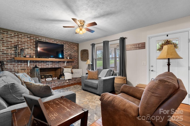 living room with a textured ceiling, ceiling fan, and wood finished floors