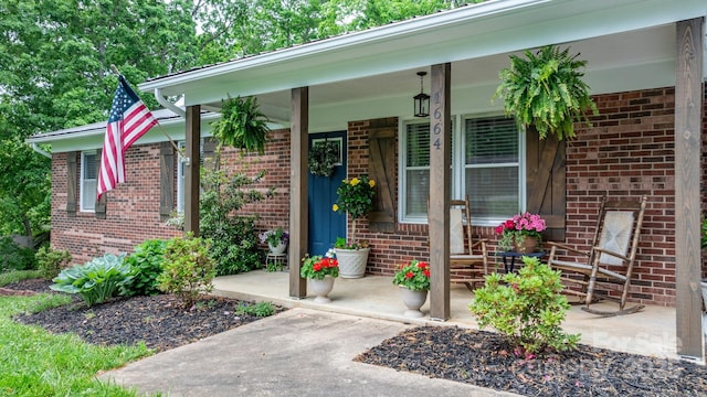 entrance to property featuring a porch and brick siding