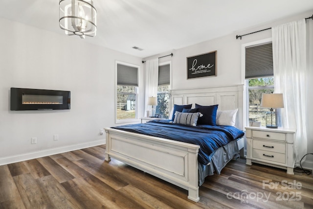 bedroom with visible vents, dark wood finished floors, baseboards, and an inviting chandelier