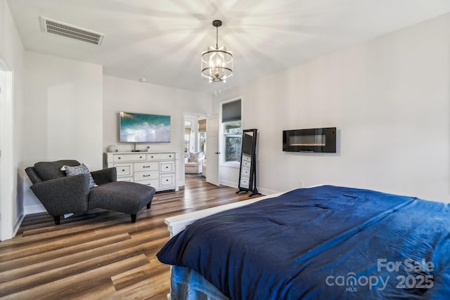 bedroom featuring visible vents, baseboards, wood finished floors, and a notable chandelier