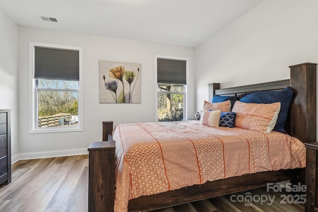 bedroom with visible vents, baseboards, and wood finished floors