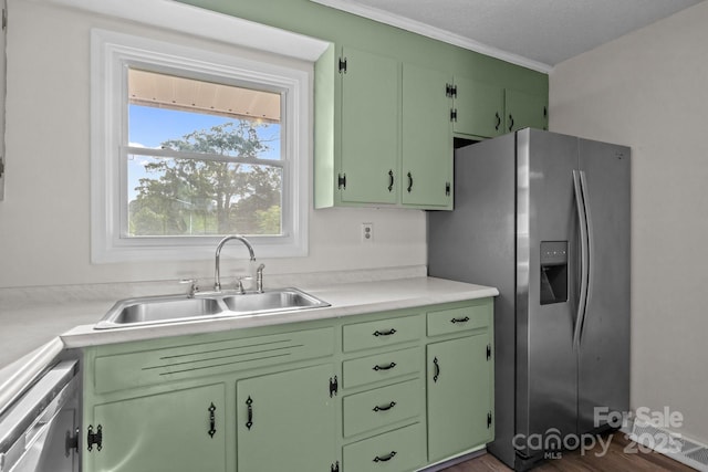 kitchen with light countertops, crown molding, appliances with stainless steel finishes, and a sink