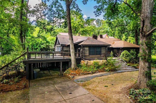 log home with log exterior, stairway, roof with shingles, concrete driveway, and a deck