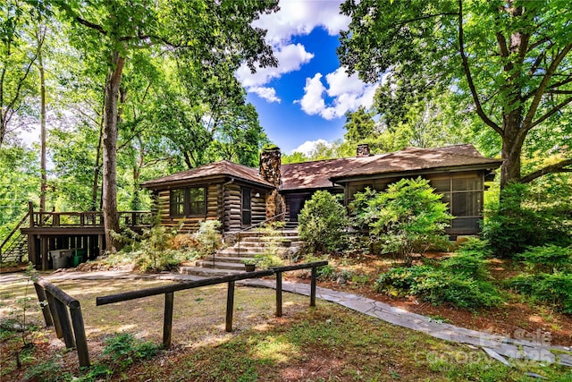 back of property with a chimney, a garage, and log exterior