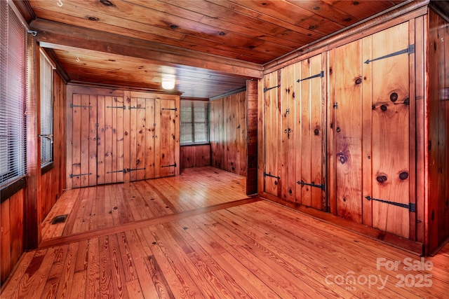 empty room featuring wooden ceiling, hardwood / wood-style floors, wooden walls, and crown molding