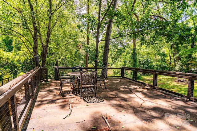 view of patio featuring outdoor dining space and a wooded view
