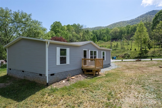 back of property featuring a yard, crawl space, and a deck