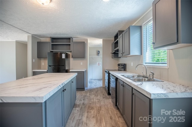 kitchen with a textured ceiling, open shelves, a sink, black appliances, and light wood-style floors