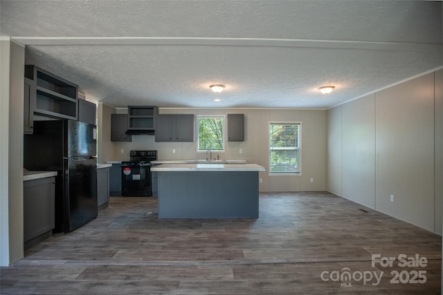 kitchen featuring a center island, open shelves, dark wood finished floors, light countertops, and black appliances