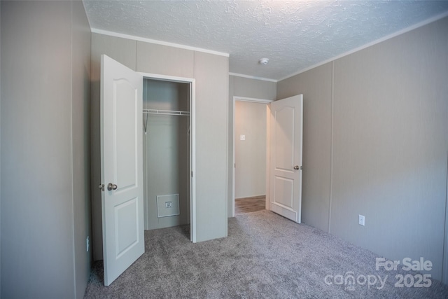 unfurnished bedroom with crown molding, carpet floors, a closet, and a textured ceiling