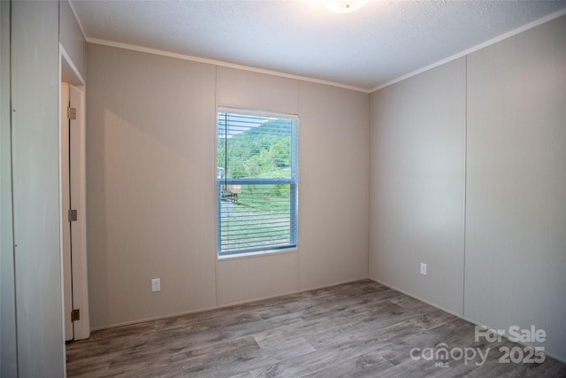 unfurnished room with ornamental molding and wood finished floors