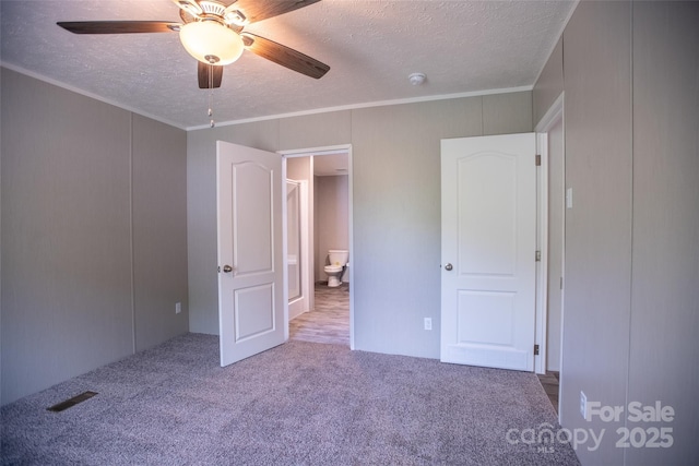 unfurnished bedroom with carpet flooring, ceiling fan, a textured ceiling, visible vents, and ornamental molding