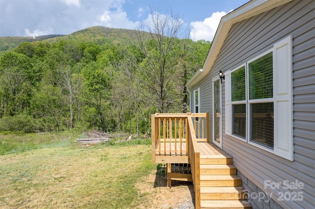view of yard featuring stairway, a deck, and a forest view