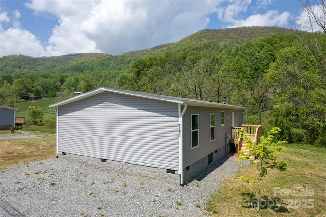 view of property exterior featuring a view of trees, a wooden deck, and crawl space