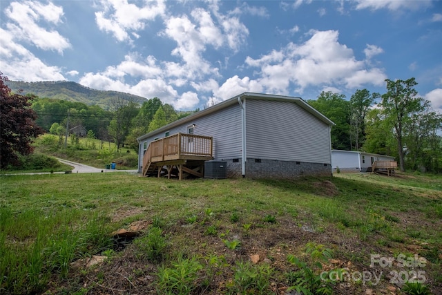 view of property exterior with a lawn, crawl space, a deck with mountain view, and central AC unit