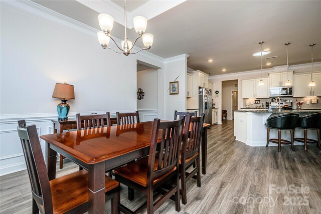 70 Cameo Dr, Flat Rock, NC 28731 - dining room with ornamental molding, light wood-style flooring, a chandelier, a wainscoted wall, and a decorative wall
