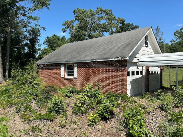 view of home's exterior with a garage, brick siding, roof with shingles, and fence