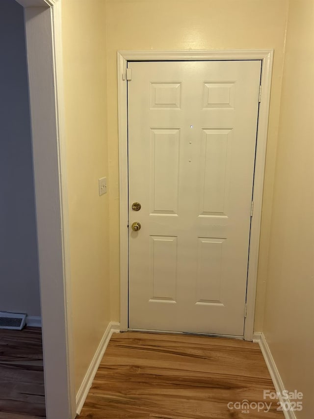 doorway featuring wood finished floors and baseboards