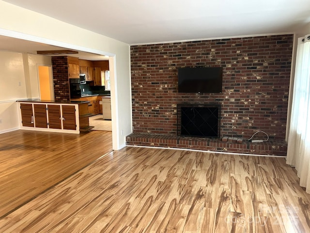 unfurnished living room featuring light wood finished floors and a brick fireplace