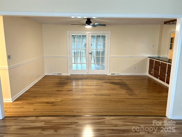unfurnished room featuring wood finished floors, ceiling fan, and baseboards