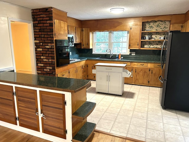 kitchen with appliances with stainless steel finishes, a sink, backsplash, dark countertops, and a textured ceiling