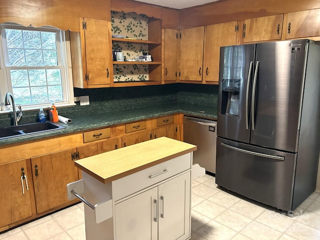 kitchen featuring stainless steel appliances, a sink, open shelves, and brown cabinets