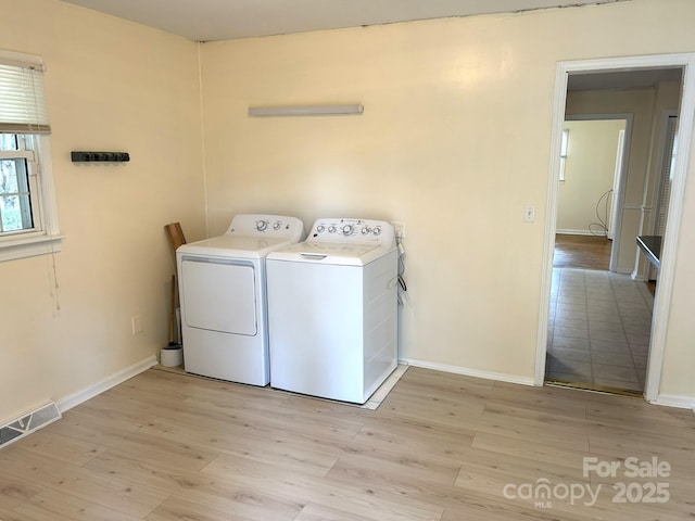 laundry room featuring washing machine and clothes dryer, light wood finished floors, and baseboards