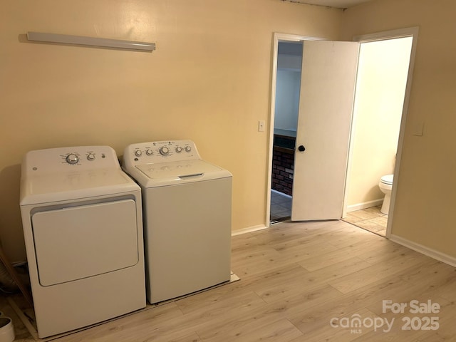 laundry room with washer and dryer, light wood finished floors, and baseboards