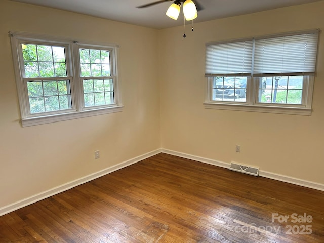 spare room with baseboards, dark wood finished floors, and ceiling fan