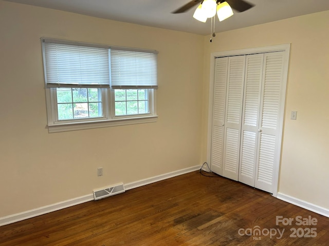 unfurnished bedroom with baseboards, dark wood finished floors, a closet, and ceiling fan