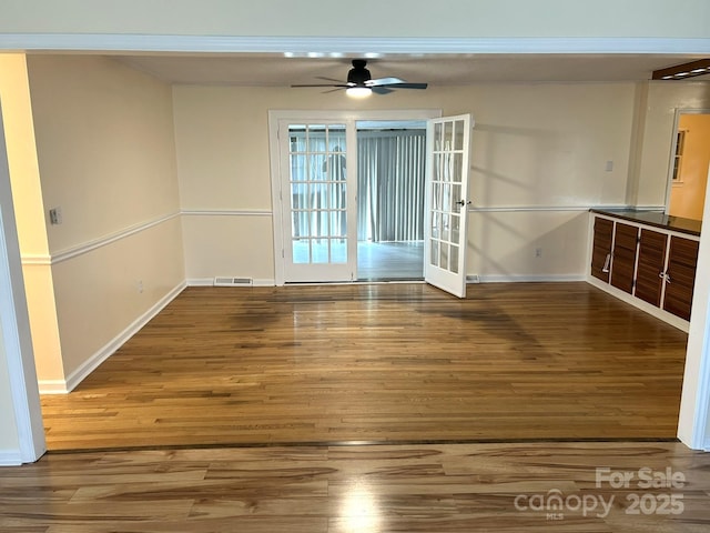 unfurnished room featuring baseboards, wood finished floors, a ceiling fan, and french doors