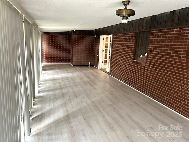 spare room with brick wall and wood finished floors