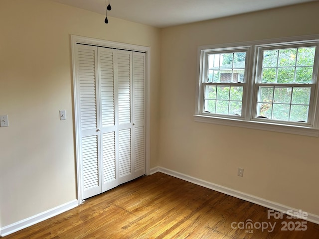 unfurnished bedroom with baseboards, a closet, and light wood-style floors
