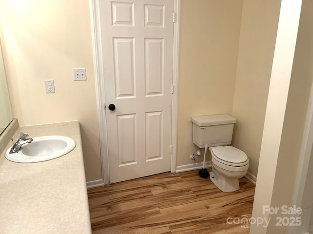bathroom with wood finished floors, toilet, baseboards, and vanity